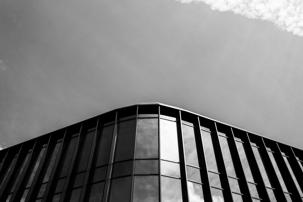 Voiture allemande haut de gamme, symbole de luxe, devant un bâtiment moderne en architecture contemporaine.