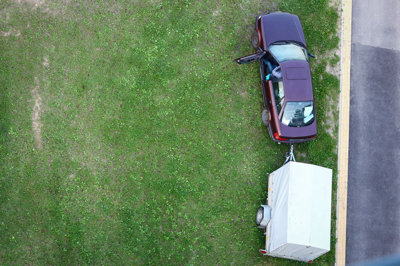 Voiture avec attelage et caravane garées devant atelier spécialisé en réparations et équipements de remorques.