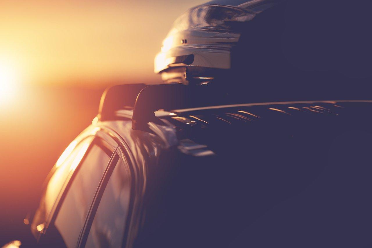 Voiture équipée d’un coffre de toit et porte-skis pour un voyage en toute sécurité sur autoroute.