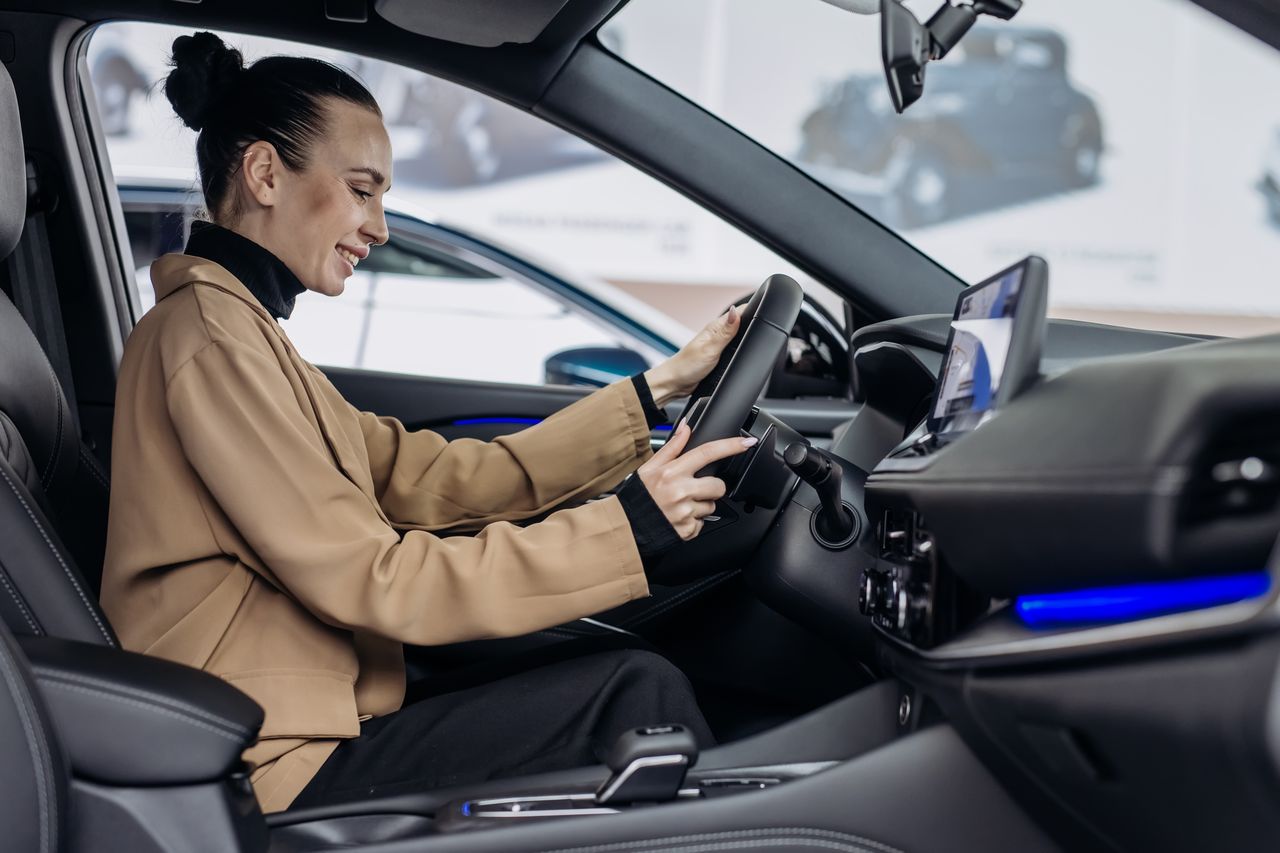 Voiture neuve en ville avec capteurs et icônes de sécurité active, confort et technologie avancée.