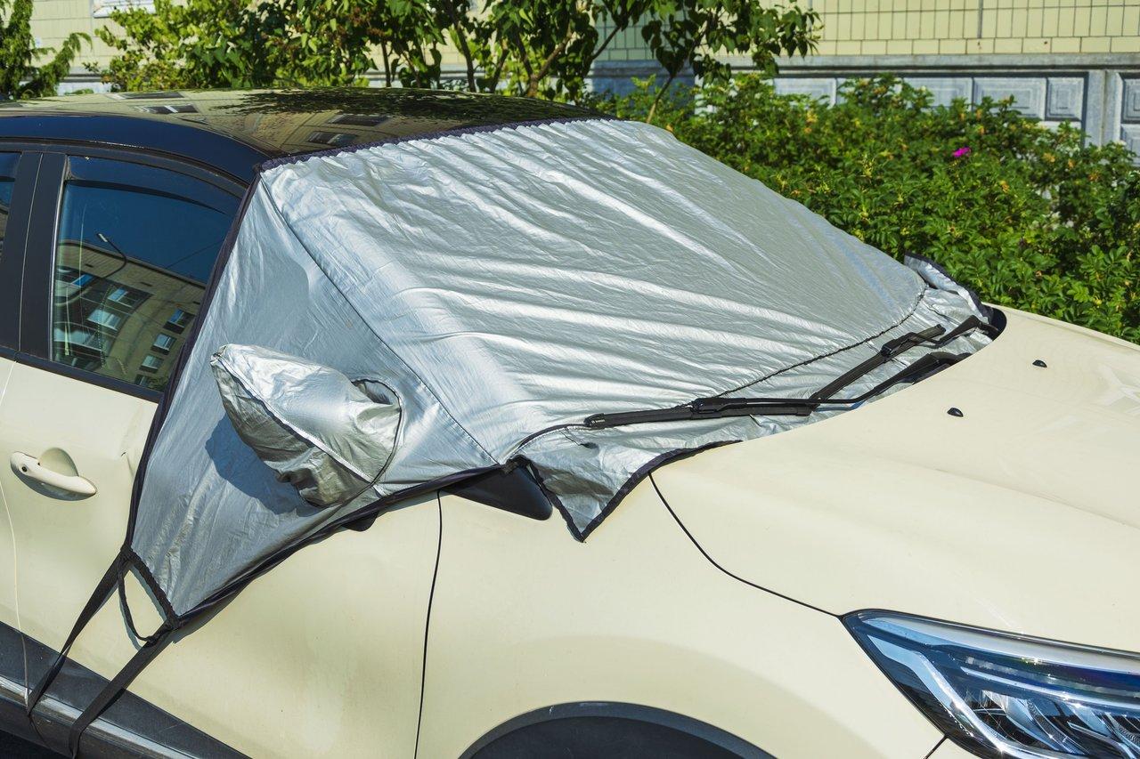 Voiture protégée contre le gel avec une bâche anti-givre et essuie-glaces relevés, assurant une meilleure car covered frost protection.