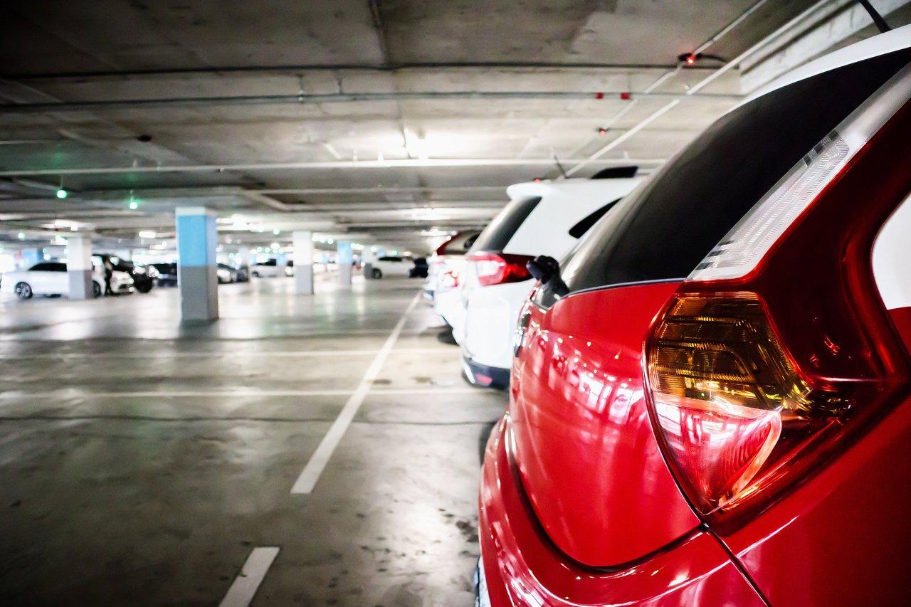 Voiture sécurisée dans un parking éclairé avec verrouillage manuel et bloque-volant visible, solution anti-vol économique.