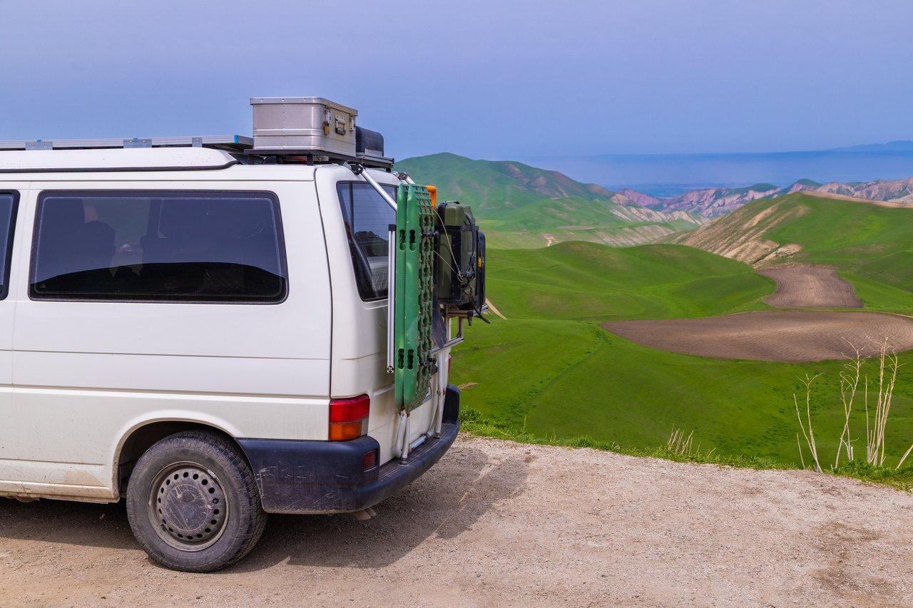 Vue de face d’un camper van Fiat Ducato aménagé en camping-car sur une route de campagne en pleine nature.