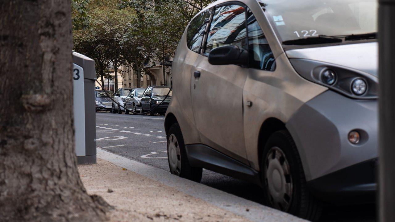 Vue dynamique d’un parking urbain rempli de véhicules hybrides compacts et SUV familiaux en 2025.