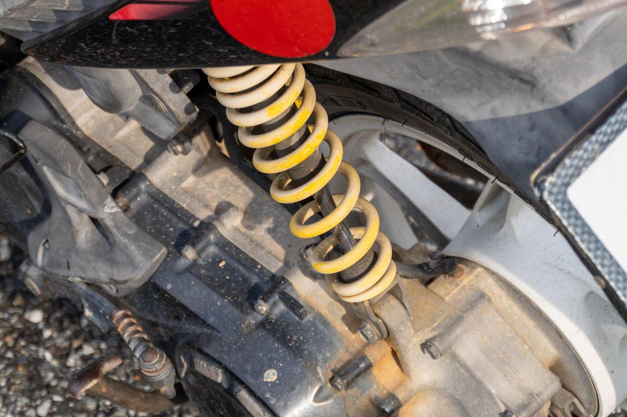 Vue rapprochée d'une suspension moto avec réglages précis de précharge, compression et détente en milieu urbain.